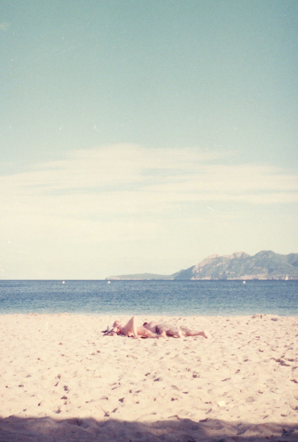 uma pessoa deitada em uma praia com uma prancha de surf