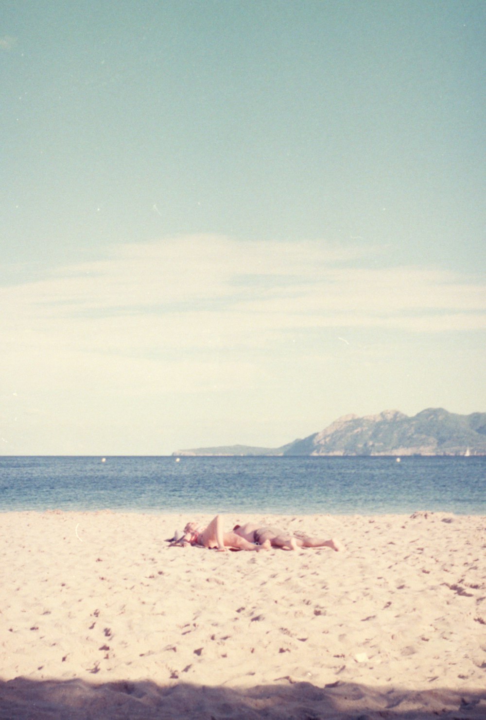 a person laying on a beach with a surfboard