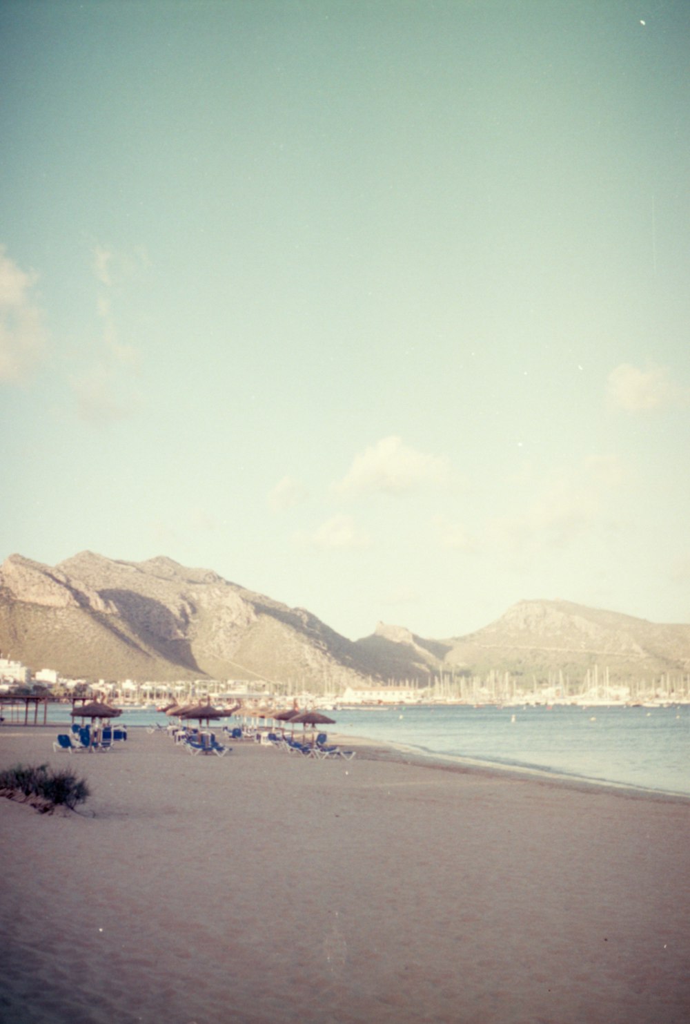 a sandy beach with mountains in the background