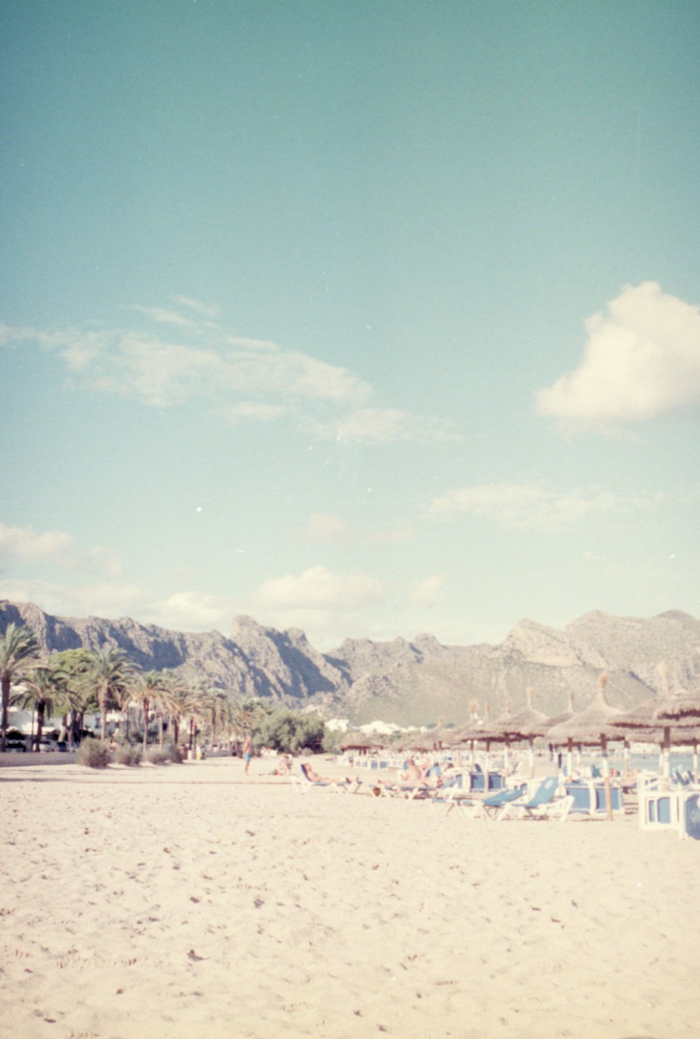 a beach with chairs and mountains in the background