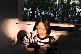 Close-up of a smiling woman watching art top 10 videos on her tablet in a sunlit room filled with plants.
