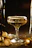 Elegant black and gold cocktail glass with a shimmering garnish, set against a sleek dark background.