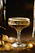 Elegant black and gold cocktail glass with a shimmering garnish, set against a sleek dark background.