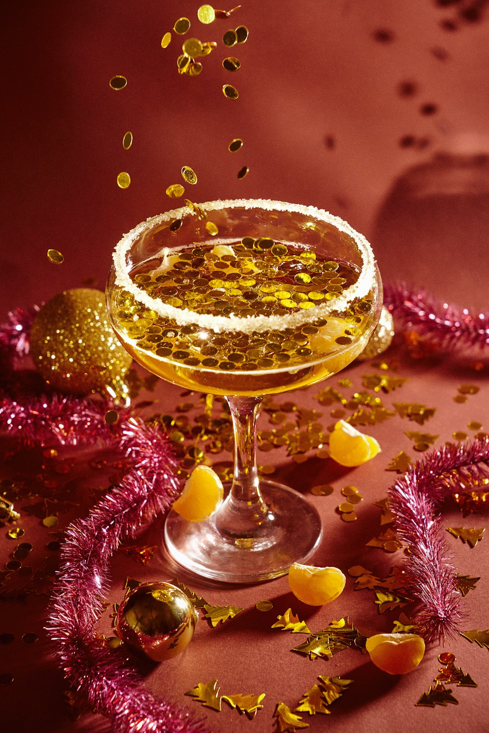 a glass filled with a drink surrounded by confetti