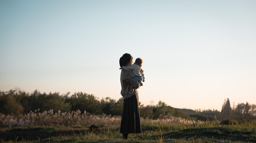 a woman holding a baby in a field