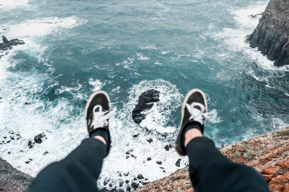 uma pessoa em pé no topo de um penhasco perto do oceano