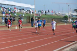 Young athletes sprinting fiercely on a rain-speckled track, muscles taut in competition