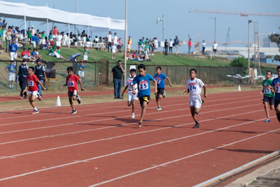 Young athletes sprinting with determination under a bright summer sky at a track meet.