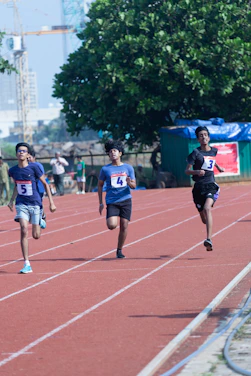 Young athletes sprinting on a sunny track with a coach encouraging them.