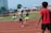 A young athlete sprinting on a track with a coach guiding nearby.