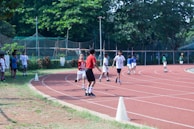 A coach encouraging children as they prepare for a relay race on the track.