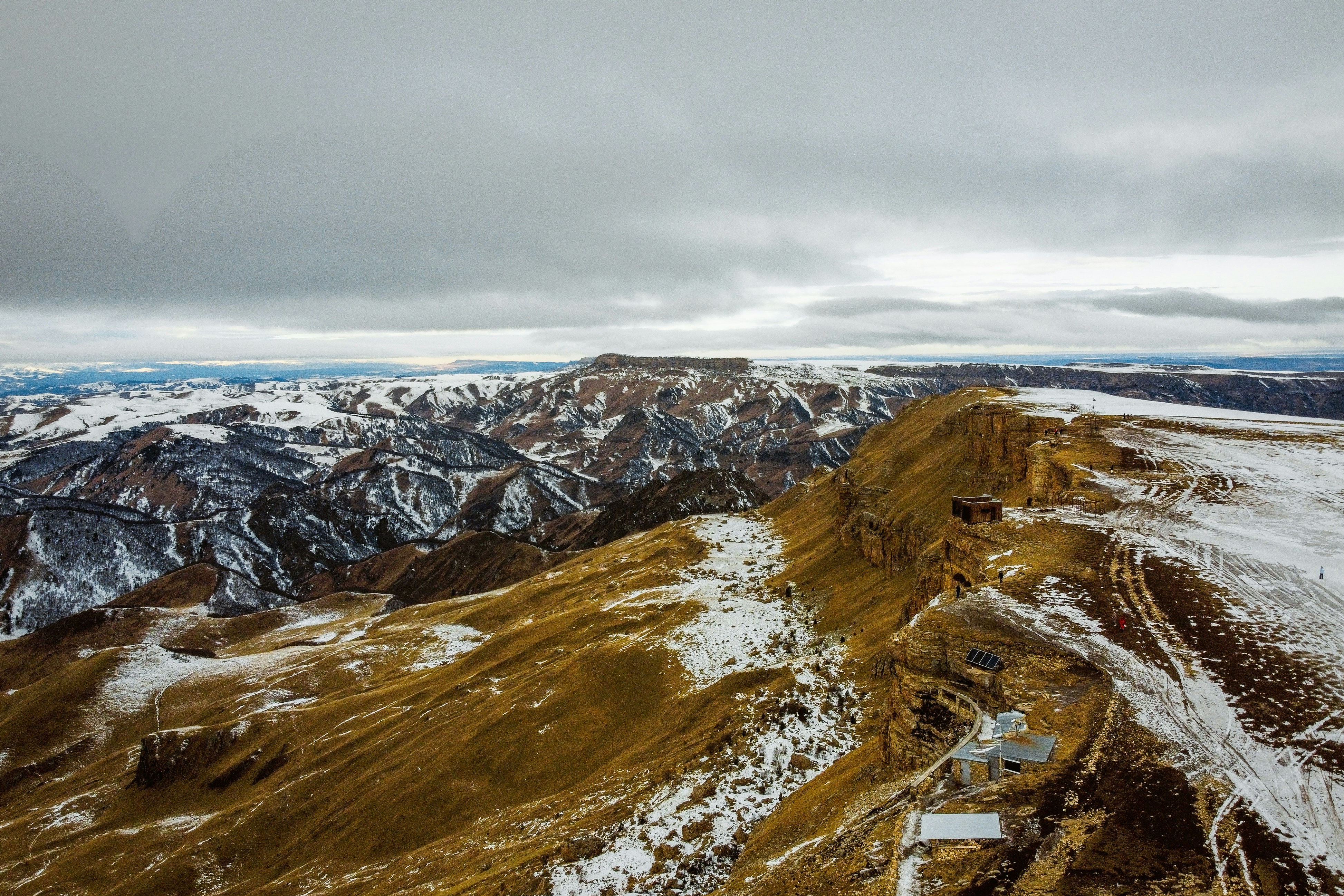 An aerial view of a mountain range with snow on the ground photo – Free ...