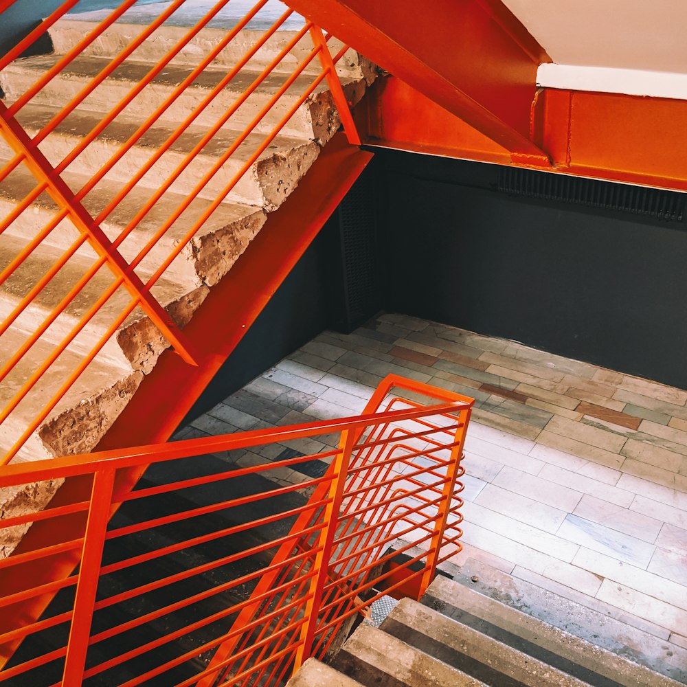 a staircase with orange railings next to a tiled floor