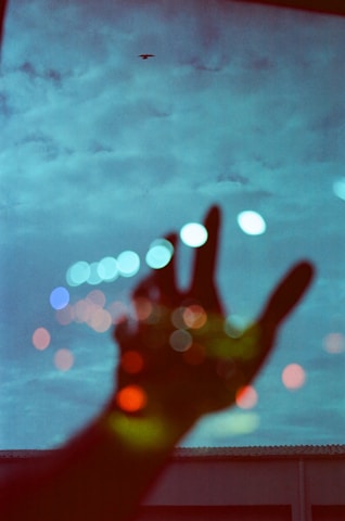 a person is holding their hand up in front of a window