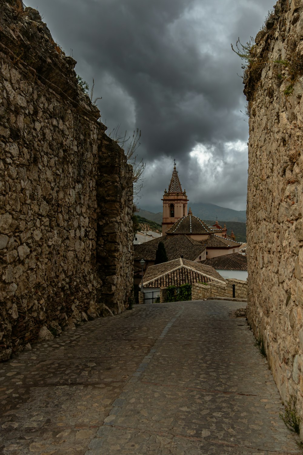 a cobblestone street with a clock tower in the background