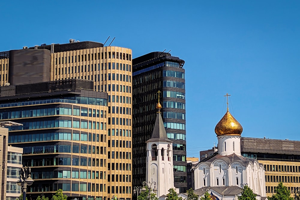 a church steeple in front of a row of tall buildings
