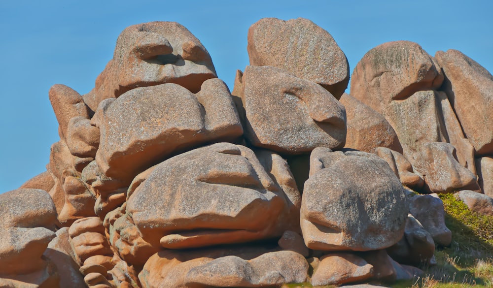 un grand groupe de rochers assis au sommet d’une colline couverte d’herbe