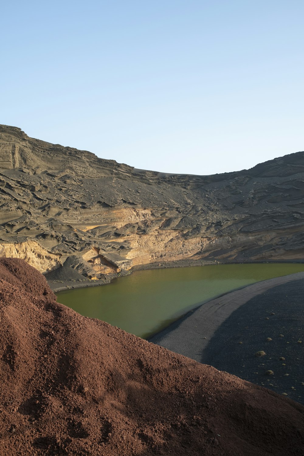 a large mound of dirt next to a body of water