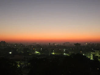 A charcoal-hued city skyline at twilight, with subtle bronze accents from the setting sun reflecting on glass buildings.
