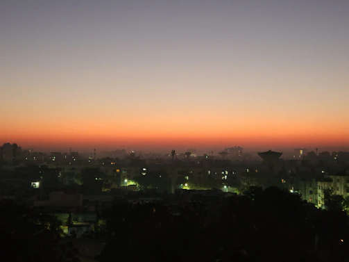 A charcoal-hued city skyline at twilight, with subtle bronze accents from the setting sun reflecting on glass buildings.