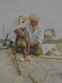 Portrait of an elderly craftsman smiling softly, surrounded by his handcrafted mandar drums.
