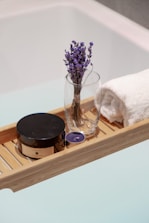 a wooden tray with a vase of flowers and a towel on it