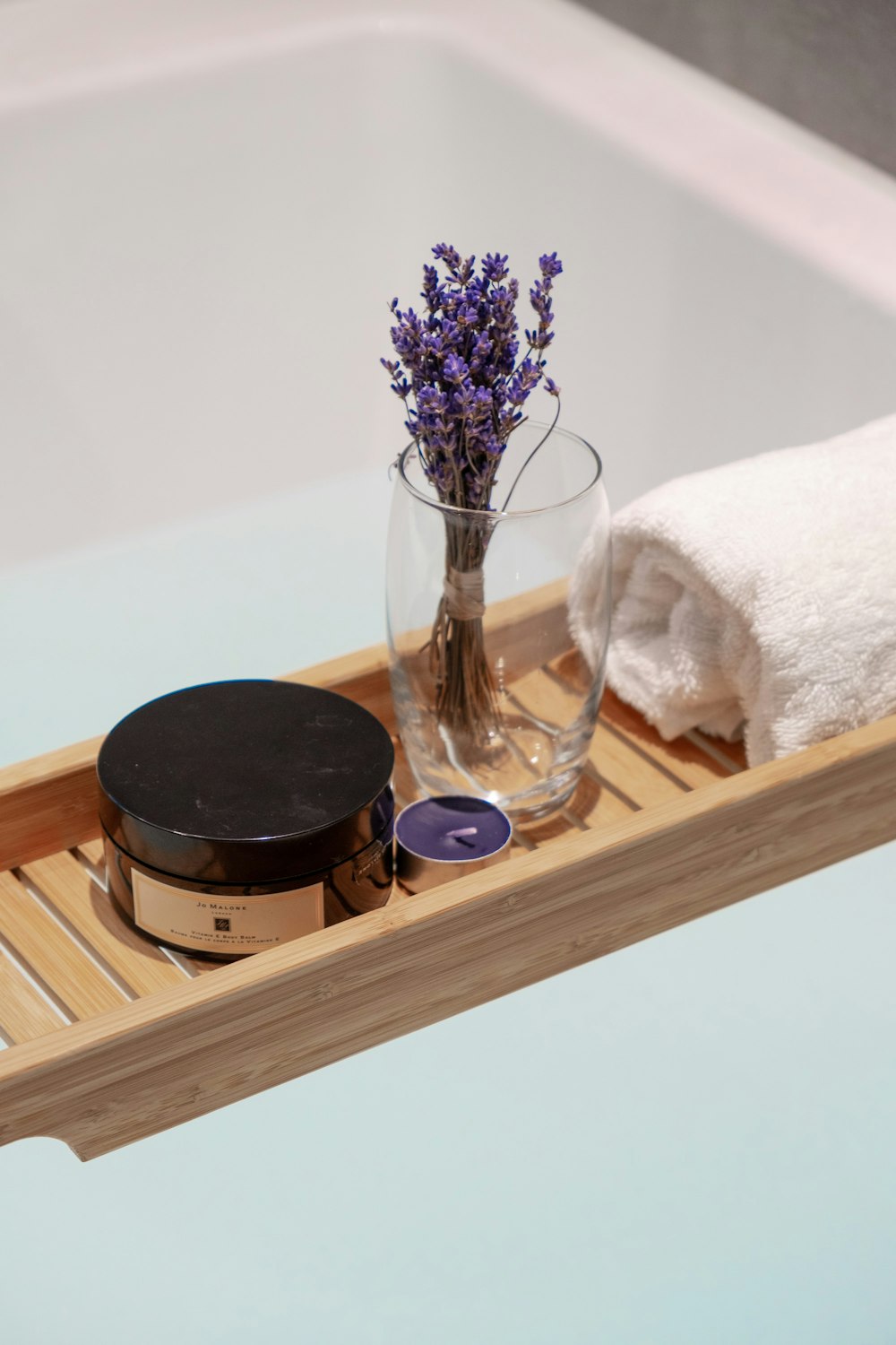a wooden tray with a vase of flowers and a towel on it