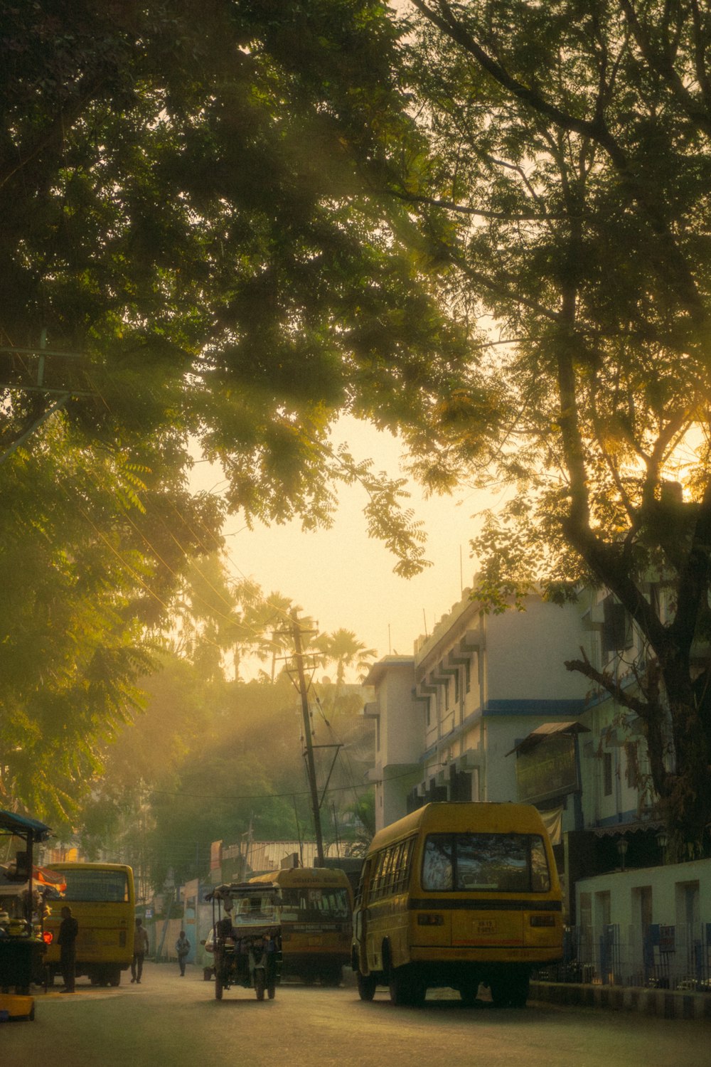 a group of buses driving down a street next to tall buildings