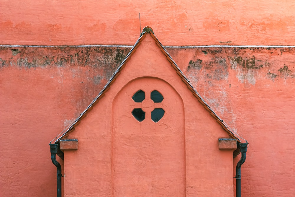 a pink wall with a small window and a metal frame