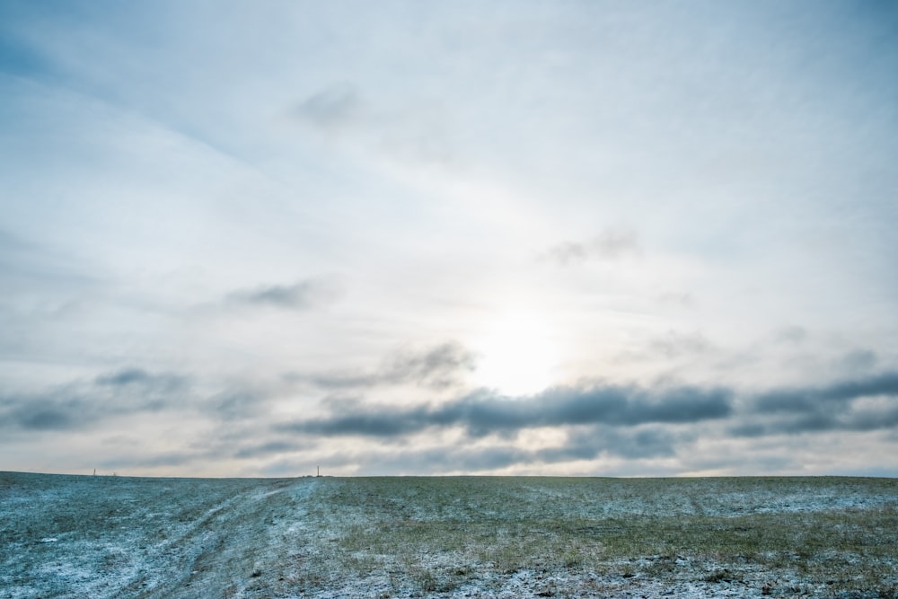 the sun shines through the clouds over a snow covered field