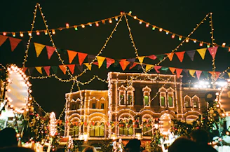 Colorful festive street lights illuminating a town square at night.