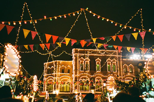 Colorful festive street lights illuminating a town square at night.