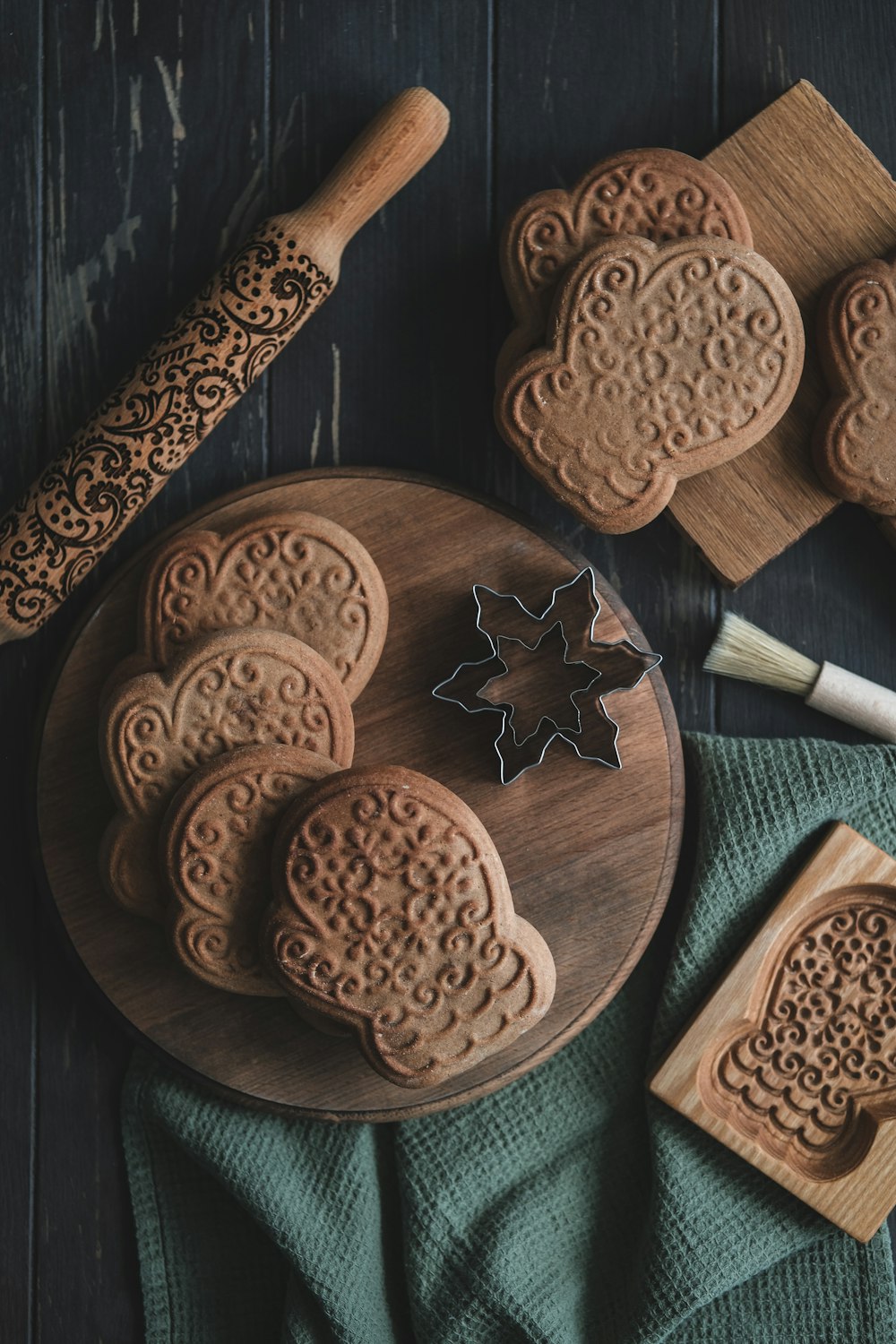 a wooden cutting board topped with cookies next to a cookie cutter