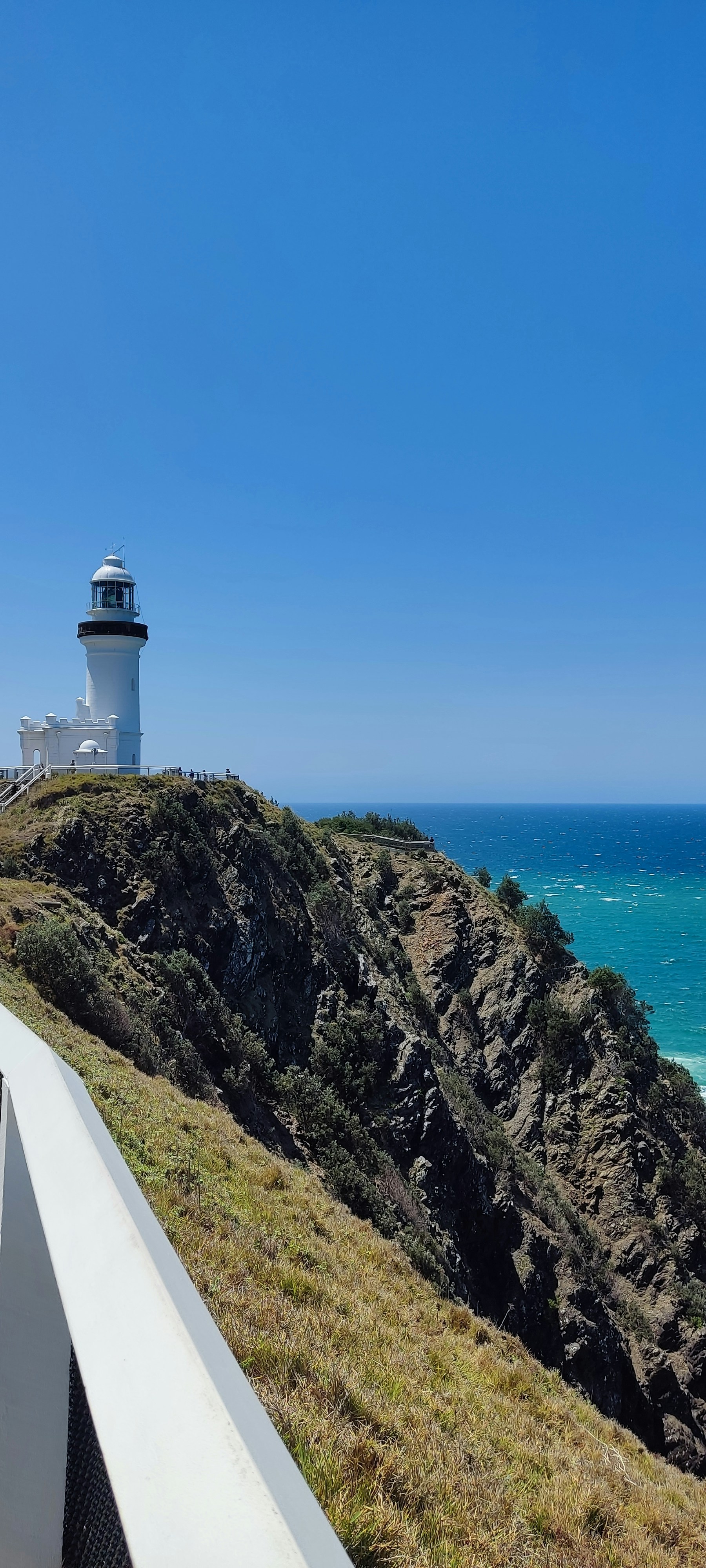 a lighthouse on top of a hill next to the ocean