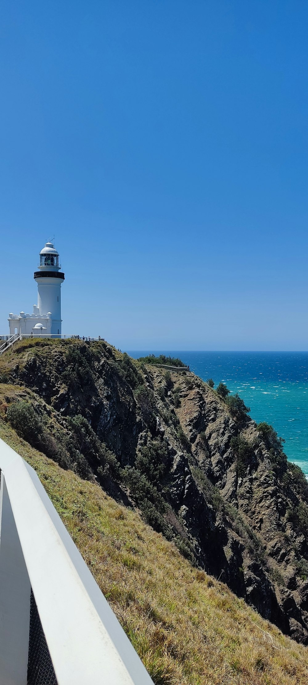 a lighthouse on top of a hill next to the ocean