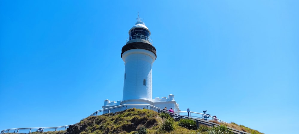 a white and black lighthouse on top of a hill