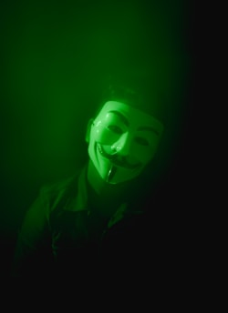 a man wearing a green mask in the dark