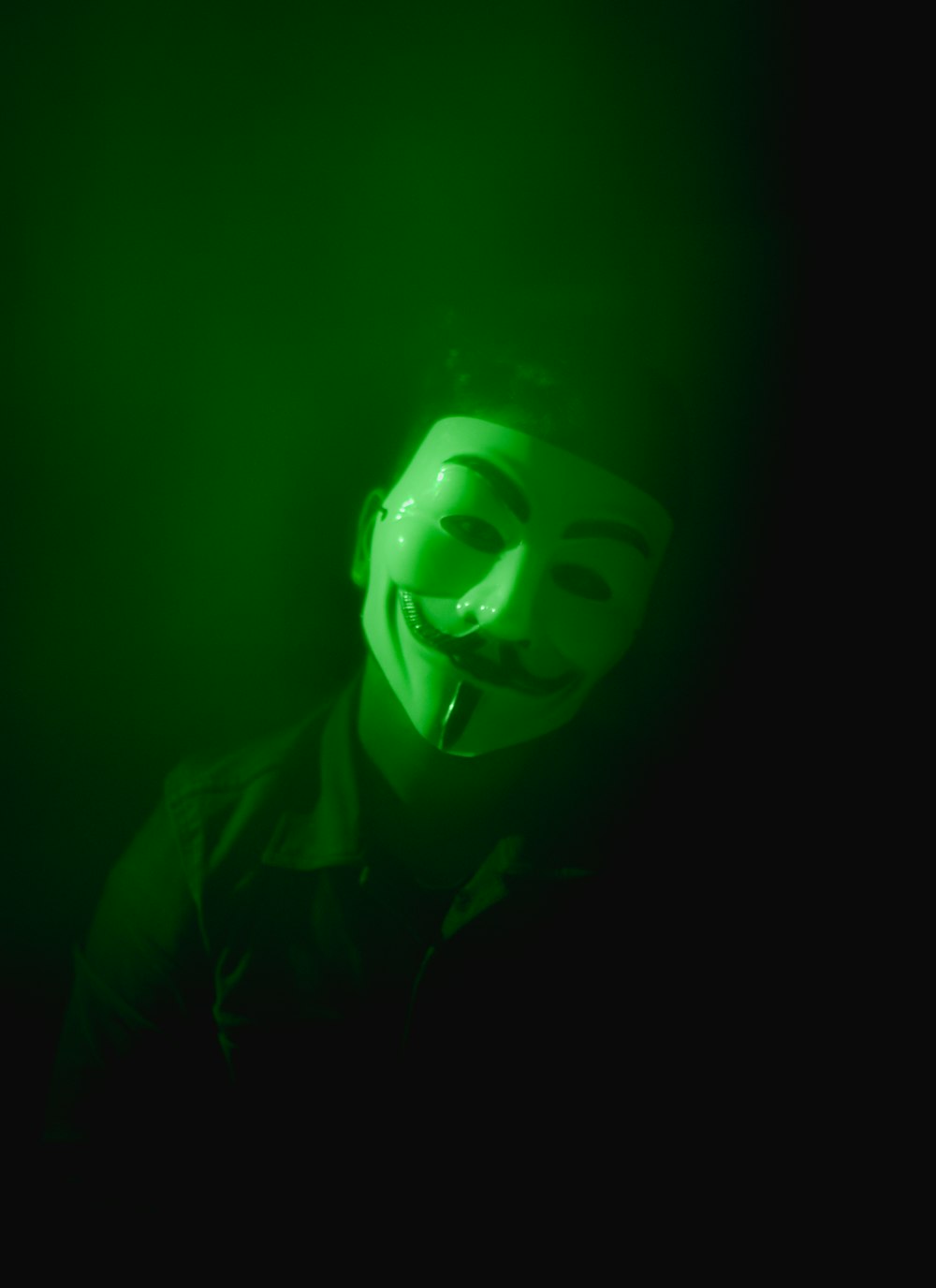 a man wearing a green mask in the dark