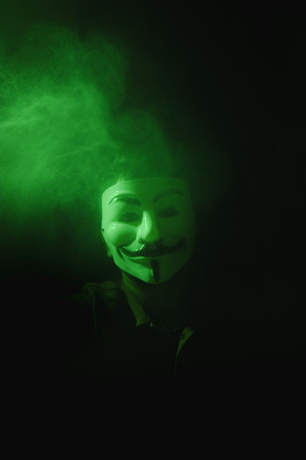 a man wearing a green mask in the dark