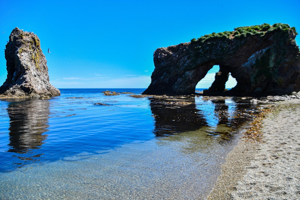 a rock formation in the water near a beach