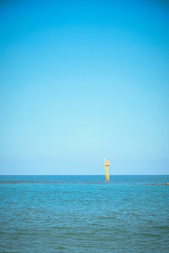 Ocean monitoring buoy transmitting data under a clear blue sky.