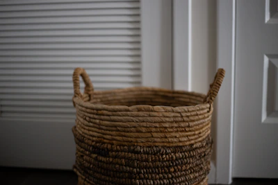 A sleek, modern laundry basket with handles placed near a bright window.