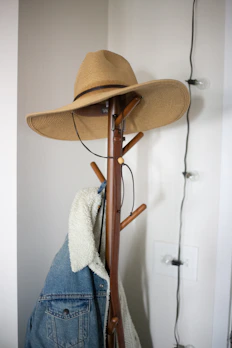 A colorful bucket hat hanging on a vintage coat rack by a sunny window.