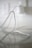 A close-up view of a white electrical cord or cable resting on a reflective surface. The background is out of focus, showing part of an electrical outlet, adding a sense of depth.