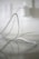 A close-up view of a white electrical cord or cable resting on a reflective surface. The background is out of focus, showing part of an electrical outlet, adding a sense of depth.