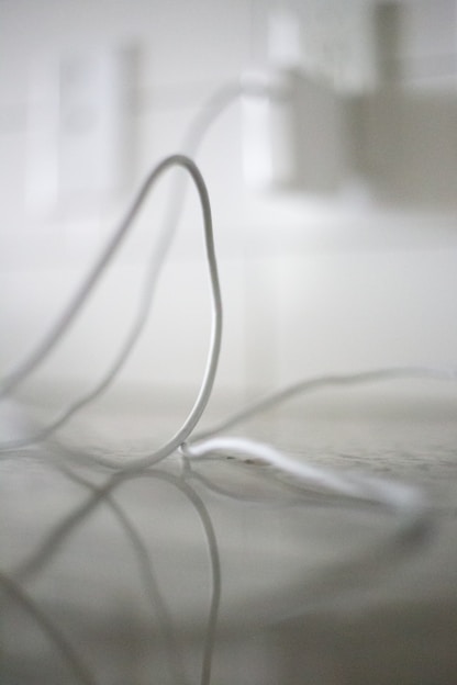 Close-up of a thick power cable coiled neatly on a wooden surface.