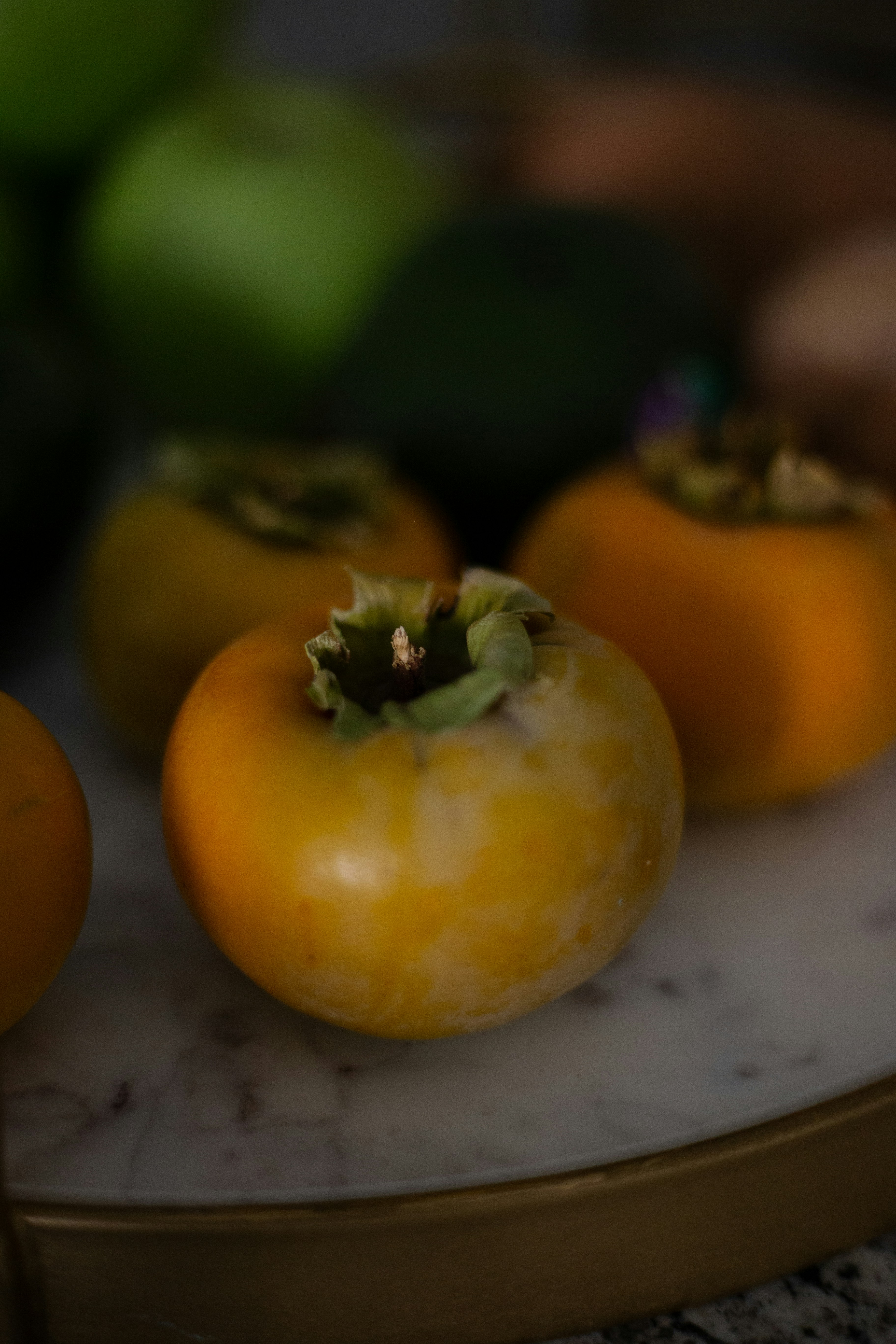 three orange tomatoes sitting on top of a marble counter