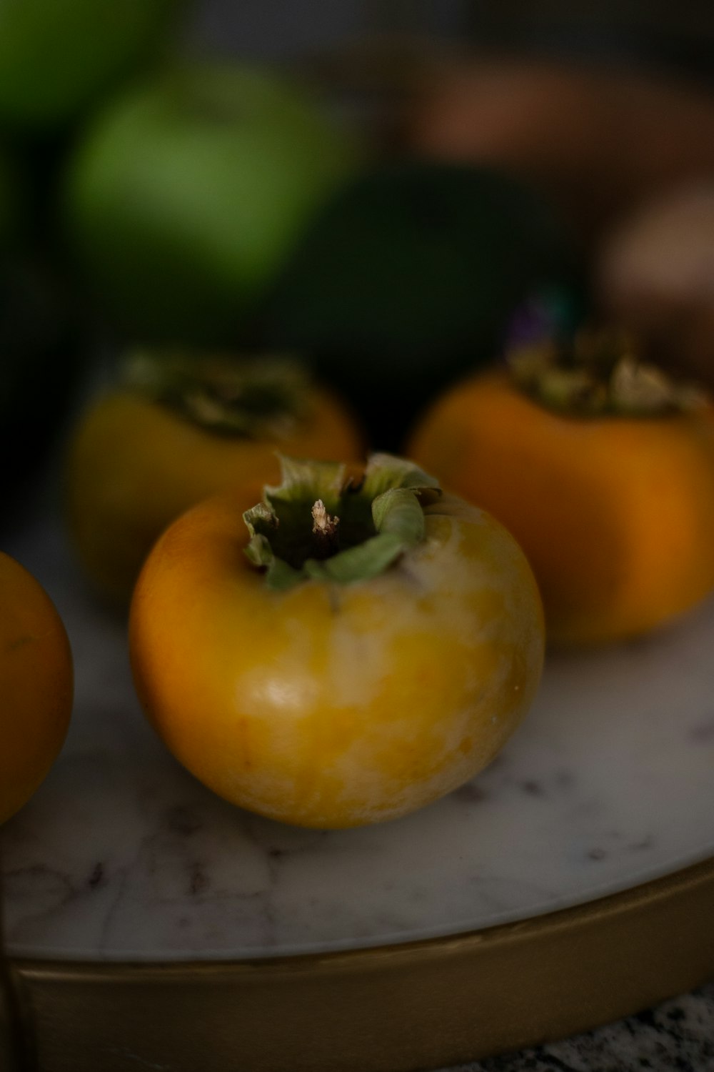three orange tomatoes sitting on top of a marble counter