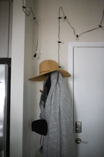 An over-door hanger holding cozy scarves and hats in a softly lit hallway.