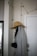 A coat hanger on a wall holds a grey coat and a wide-brimmed tan hat. Above, a string of lights with visible cords drapes along the wall. A partially visible door is on the right, featuring a modern handle. The setting appears to be indoors, possibly an entryway or hallway.